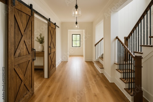 A well-lit modern farmhouse interior featuring a barn door, staircase, hardwood floors, and pendant lights. Represents home, design, and architecture. Ideal for real estate or interior design themes.