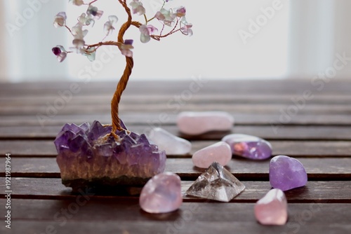 Zen atmosphere with candles and gemstones. Amethyst with polished crystals in pyramid and a prosperity tree on wood background. Calm vibes with minerals and candles. Meditation and spirituality.