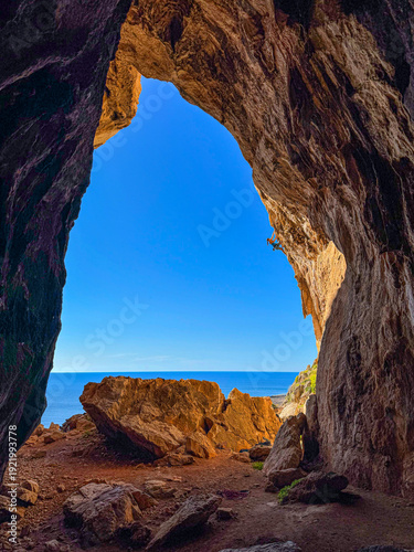 Fotografie LOW ANGLE VIEW: Strong female climber tackles steep limestone tufas at the entrance of Grotta del Cavallo