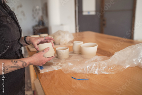 Artist inspecting handmade clay pottery  
