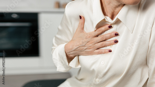Foto A mature woman feels chest pain while seated in her living room