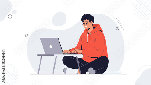 Young man working on laptop, sitting cross-legged with laptop table