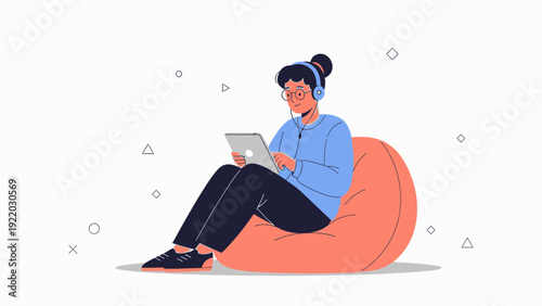 Young person with headphones using tablet while sitting on beanbag chair
