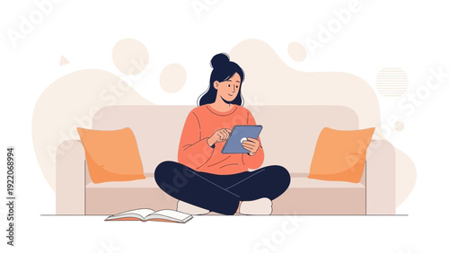 Young woman using tablet on sofa, cross-legged, with book and pillows