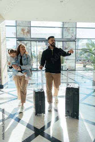 Family arriving at hotel lobby beginning vacation with luggage
