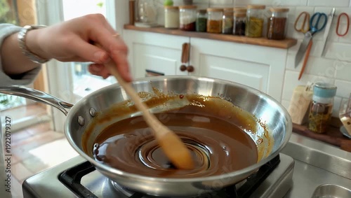 Delicious 4K Ultra HD slow motion cooking video of a cook actively stirring a caramel paste in a pan during the crucial process of creating delicious caramel sweets showing the melting butter and
