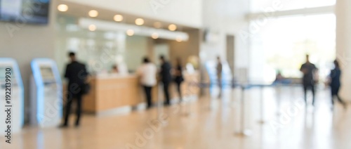 A blurred scene captures a busy bank or reception area, featuring diverse customers and staff interacting at various service counters, reflecting efficient public service.