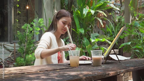 Authentic Gen Z happy young adult asian woman painting brush on canvas at workshop cafe creativity lifestyle therapy
