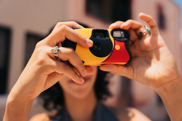 Unrecognizable woman taking a photo with a disposable camera.