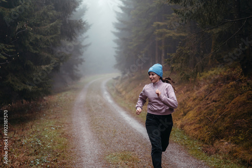 Smiling woman running and exercising in the forest