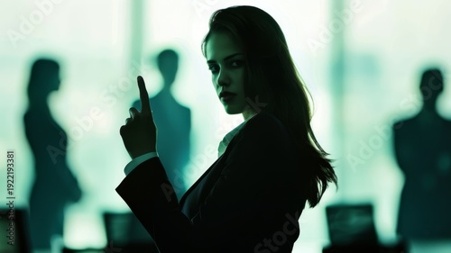 Intense businesswoman in silhouette with green hue makes a 'finger gun' gesture in a boardroom