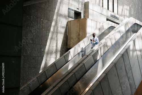Man Ascending with Drink and Phone in Modern Space