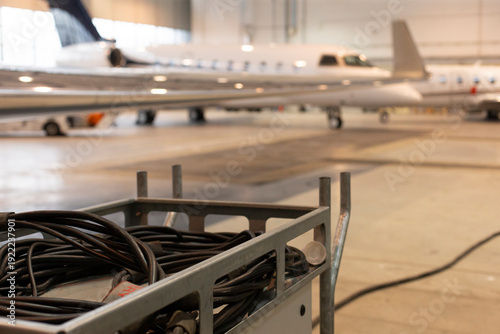 Lowangle gulfstream g engine and wing with ground cart and cable foreground, operational hangar prep for departure, power hookup and technician workflow implied