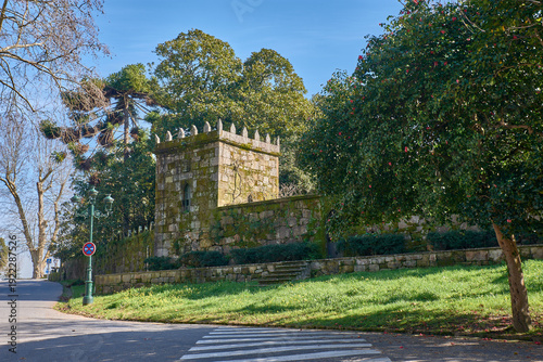 Historic wall with a granite tower surrounded by lush vegetation in Castrelos Park