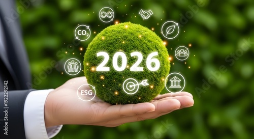 A hand holding a green globe with 2026 and sustainability symbols displayed