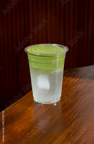 Refreshing Matcha Latte in a Clear Plastic Cup on a Wooden Surface