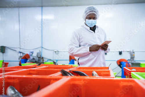Photos Quality control inspector using digital tablet for production data entry at seaf