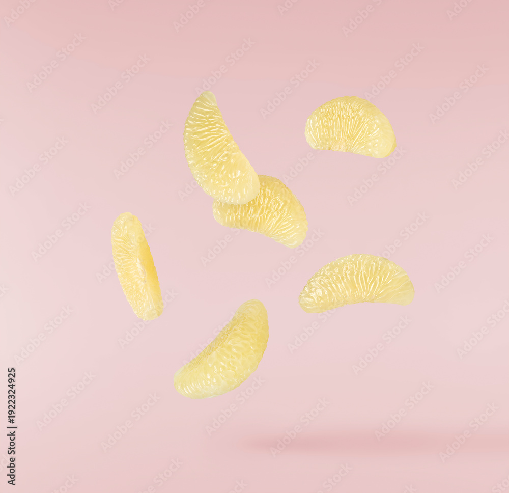Fototapeta premium Levitating peeled segments of sweetie fruit or oroblanco on a pink background. Fresh juicy citrus slices flying in the air.