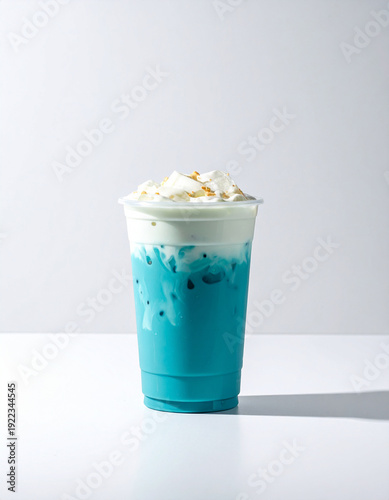 A vibrant blue iced latte topped with thick, velvety milk foam and golden crumbles. This aesthetic, refreshing drink is perfect for a cool summer treat in a minimalist setting.