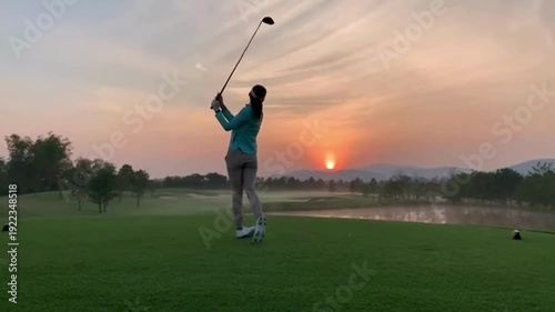 A golfer swinging a club during sunset on the golf course