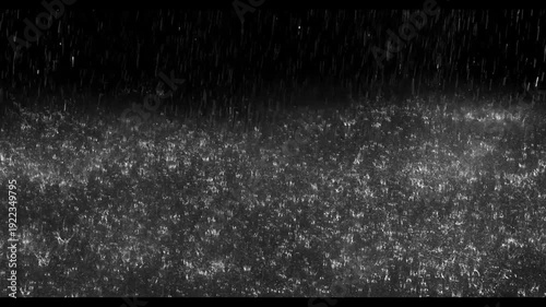 Realistic rain drops hitting the ground creating beautiful water splashes on a dark black background. Perfect cinematic rain overlay for video editing, visual effects, films, trailers, music videos