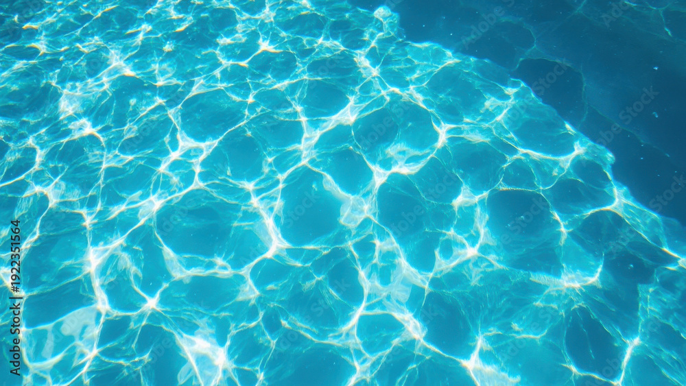 Obraz premium Sunlight shimmering on the surface of a clear blue swimming pool