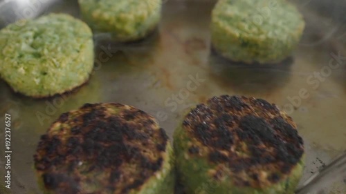 Frying chickpea and spinach patties in a frying pan, flipping to brown the other side. Vegan menu, diet food, vegetarian cafe
