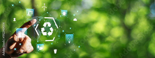 Quadro su tela Hand touching eco icons with recycling symbol on green blurred background for sustainability concept and environmental awareness theme