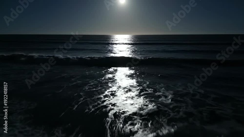 Moonlight reflecting on ocean waves at night, showcasing the gradual movement of water and shimmering light across the surface in a serene coastal setting