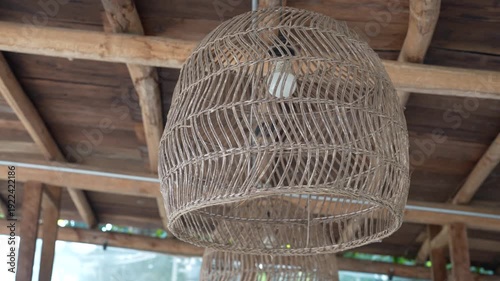Rustic woven pendant light fixture hanging from a wooden ceiling in a cozy interior space