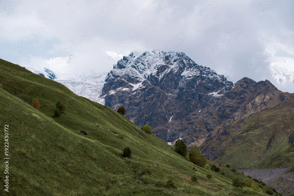 Obraz premium Majestic Snowy Peak of Adishi Glacier in Svaneti Georgia, Epic Caucasus Mountain Landscape with Green Meadows in Autumn