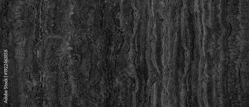 Wall with a textured surface that has grey and black color. wall has rough texture and is made of stone