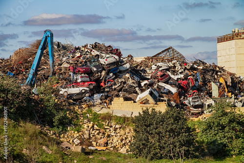 Tableau sur toile Industrial junkyard filled with stacked wrecked vehicles and scrap metal highlig