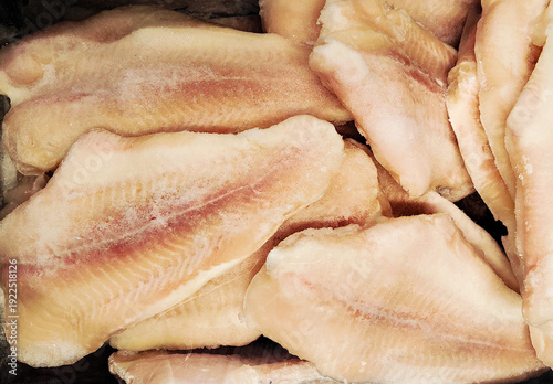 Frozen fish fillets in a supermarket or fishmonger shop. Seafood retail display and food storage concept. Vertical mobile photo. Concept seafood retail, food storage and wholesale fish distribution.