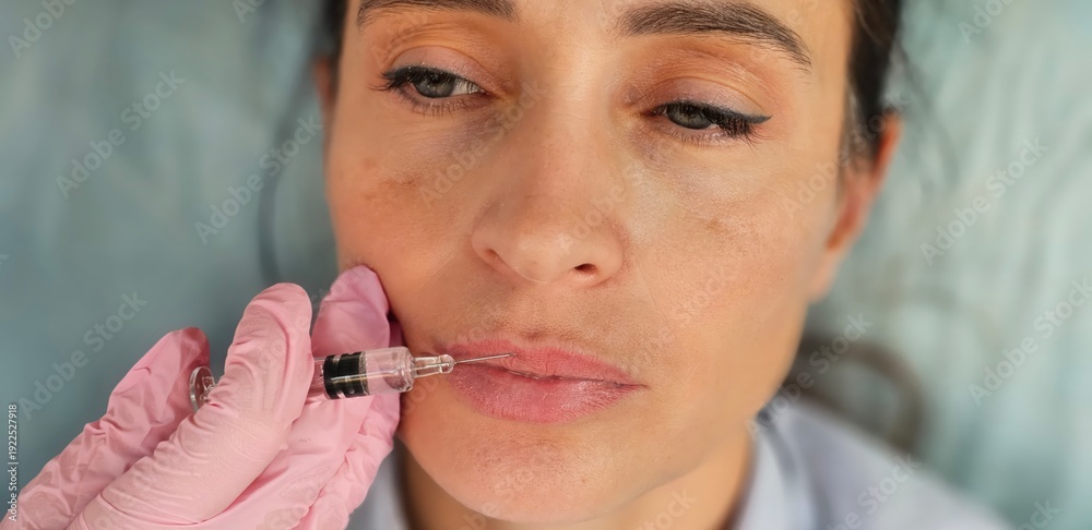 Obraz premium Doctor cosmetologist makes Lip augmentation procedure of a beautiful woman in a beauty salon