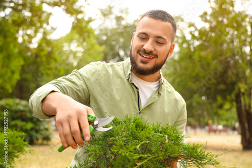 Male gardener cutting tree ...