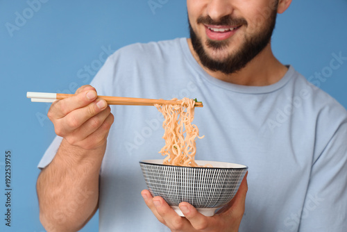 Young man eating tasty rame...