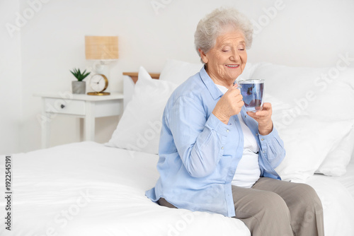 Senior woman with glass cup...