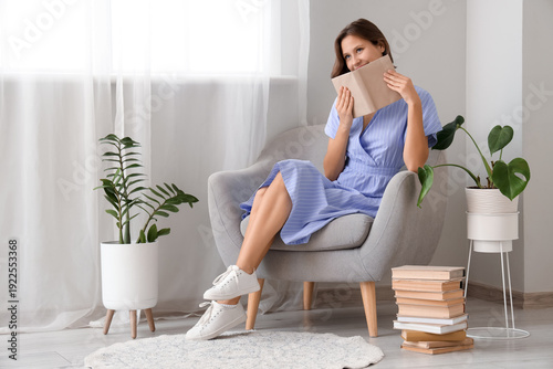 Dreamy young woman reading ...
