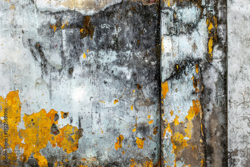 Aged weathered concrete wall with yellow and gray peeling paint texture