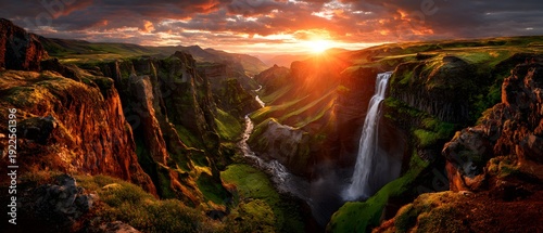 Dramatic sunset over a deep canyon with a cascading waterfall and river