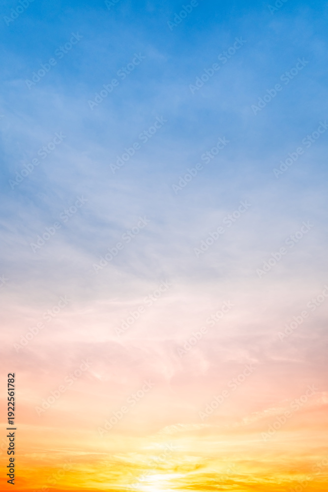 Obraz premium Beautiful sunrise sky with vibrant gradient orange and gold colors and soft blue, Clear atmosphere with wispy clouds. Peaceful, perfect for background and copy space, High resolution images Vertical