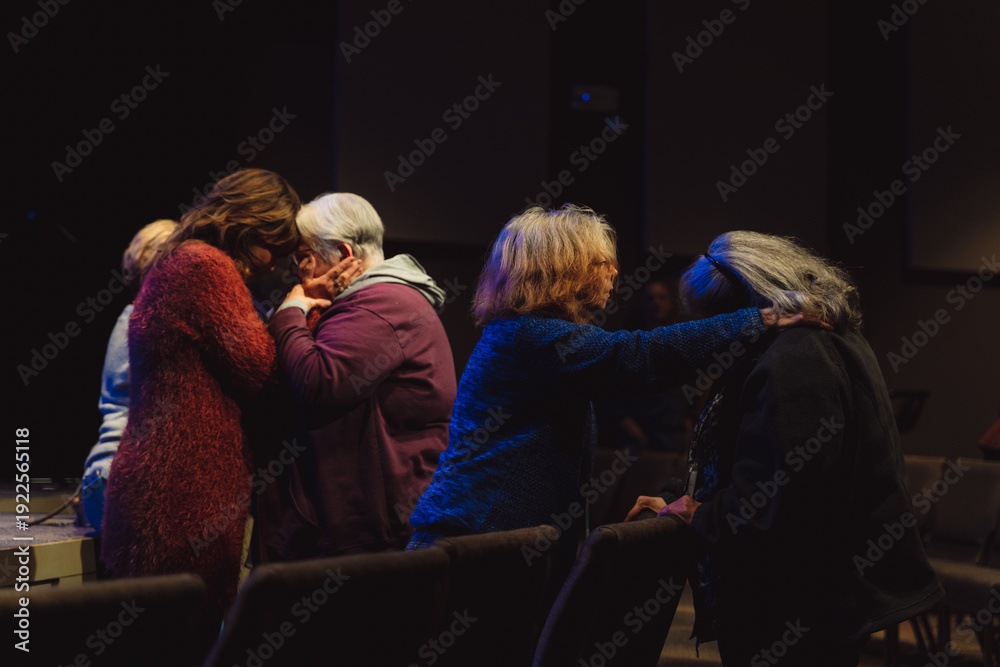 Fototapeta premium Group of women praying and offering support in a dark room