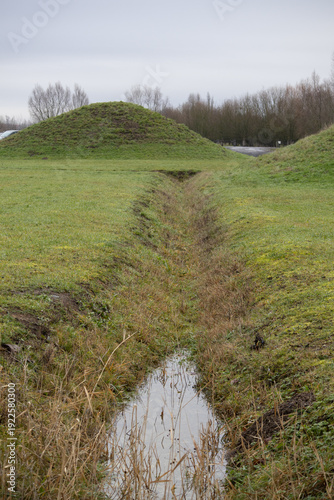 Tableau sur toile Drainage ditch with standing water leading to a grassy mound