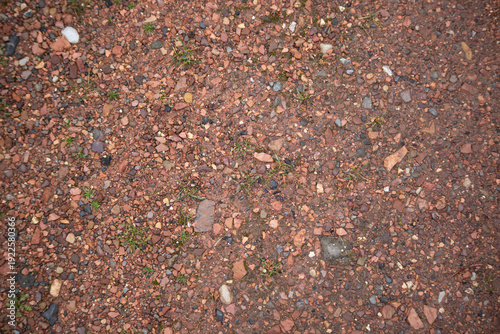 Photography Top view of reddish brown gravel and stones on the ground with sparse grass