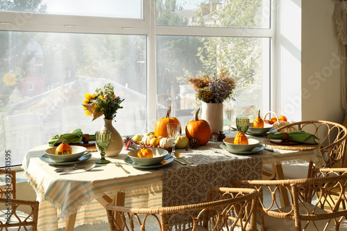 Dining table with autumn setting and pumpkins in room