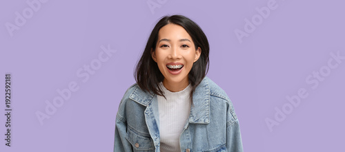 Young Asian woman laughing on lilac background