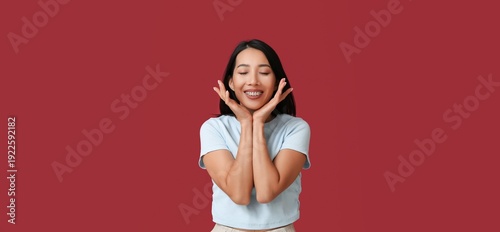Fotografía Young Asian woman smiling on red background