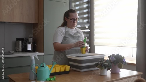 Woman prepares soil for seedlings in the kitchen, home gardening
