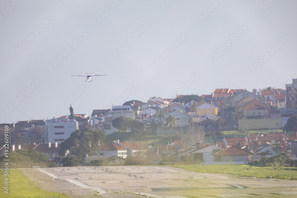 Fototapeta premium Small plane flying above urban houses